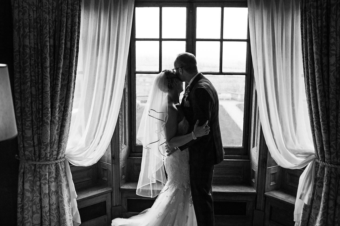 Married couple embracing at windowside
